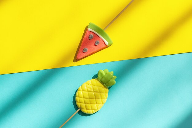 Photo summer fruits pineapple and watermelon lollipops on blue yellow background with hard light and shadow