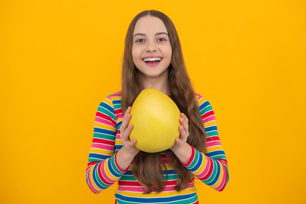 Summer fruits Teenager child girl hold citrus fruit pummelo or pomelo isolated on yellow background Kid healthy eating