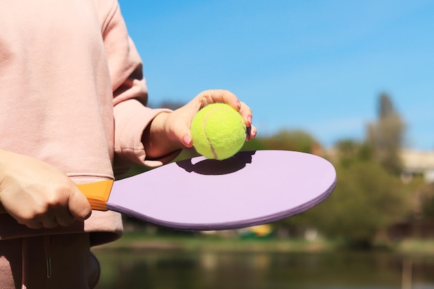 写真 夏のゲーム木製ラケットと緑のボールを持つ女性の手のクローズアップ屋外スポーツ