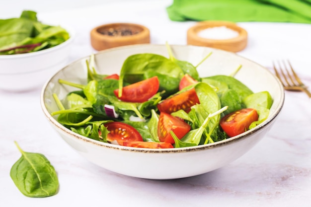 Insalata verde estiva in ciotola bianca sul tavolo grigio