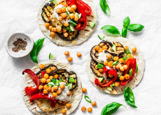 Summer grilled garden vegetables and spicy chickpeas vegetarian tortillas on a light background