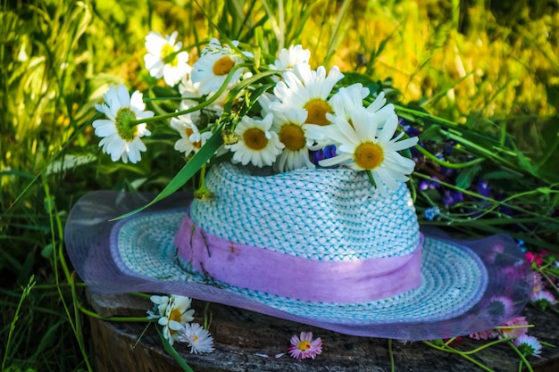 In summer, a hat and a bouquet of flowers are lying on a green meadow, grass