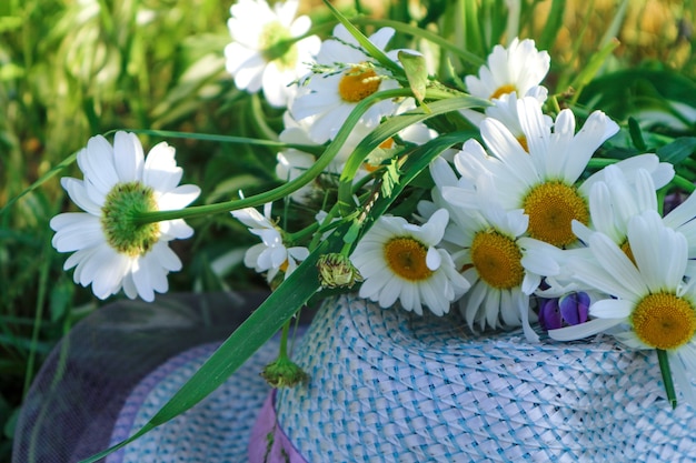 여름에는 모자와 꽃다발이 푸른 초원, 잔디에 누워 있습니다