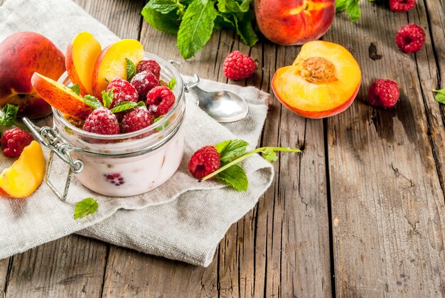 Summer healthy breakfast. Overnight oatmeal in a jar, granola, nuts, fresh raspberries and peach