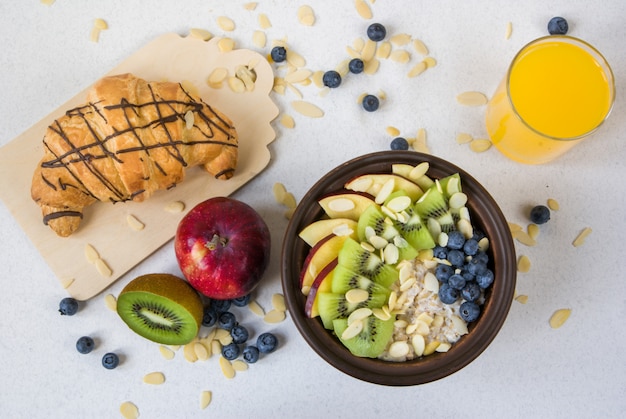 Summer healthy breakfast or snack. Oatmeal with berries and fruits, juice and krassan on a white flat table