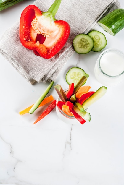 Summer healthy snack appetizer, assorted colorful fresh vegetable sticks (celery, rhubarb, pepper, cucumber and carrot) with yoghurt sauce dip 