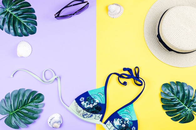 Summer holiday background. Tropical summer concept with fashion accessories, bikini, leaves on bright background.