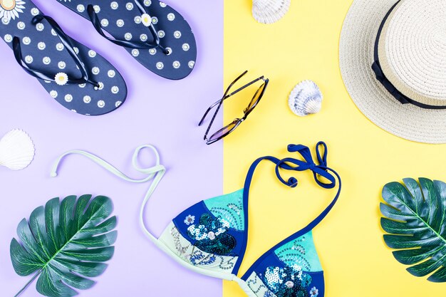 Summer holiday background. Tropical summer concept with fashion accessories, bikini, leaves on bright background.