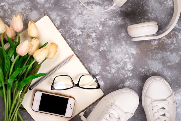 Summer holiday concept: smartphone , white sneakers, notepad, headphones, pen