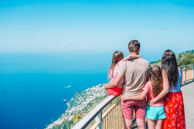 Летний отдых в Италии. Молодая семья из четырех человек на заднем плане, побережье Амальфи, Италия