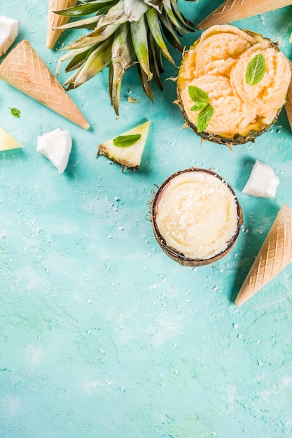 Summer holiday vacation concept, set various tropical ice cream sorbets, frozen juices in pineapple, grapefruit and coconut, light blue concrete