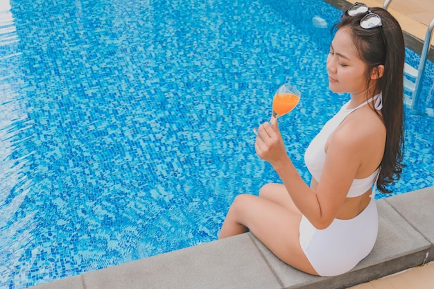 Summer holiday Young asian Beautiful woman relaxing in swimming pool at spa resort Beautiful tropical beach front hotel resort with swimming pool