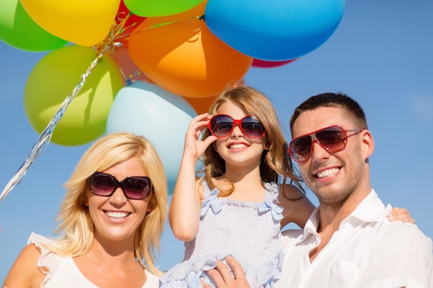 Фото Летние каникулы, праздник, концепция детей и людей - счастливая семья с красочными воздушными шарами на открытом воздухе