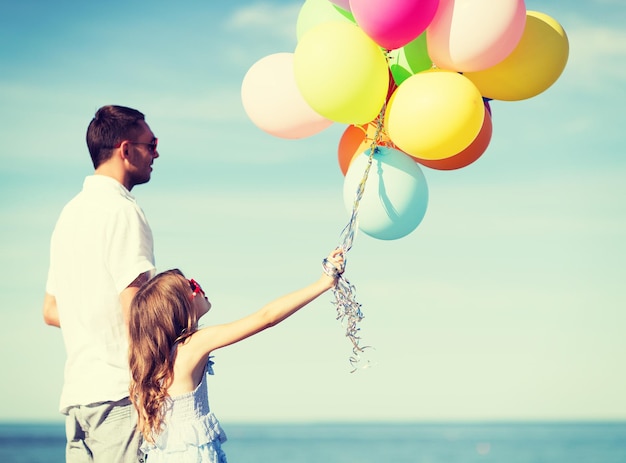 夏休み、お祝い、子供と家族のコンセプト-カラフルな風船を持つ父と娘