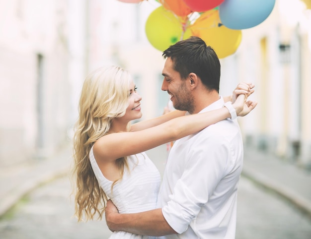 summer holidays, celebration and dating concept - couple with colorful balloons in the city