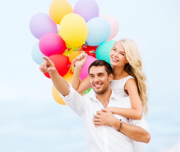 summer holidays, celebration and dating concept - couple with colorful balloons at sea side