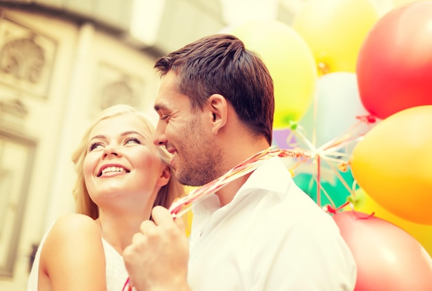 summer holidays, celebration and dating concept - happy couple with colorful balloons in the city