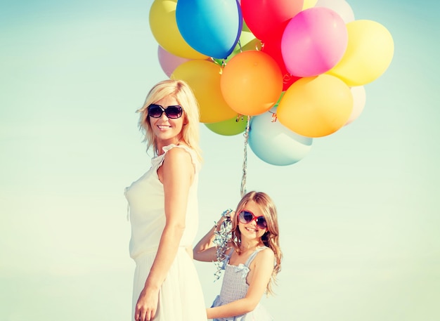 写真 夏休み、お祝い、家族、子供と人々の概念-カラフルな風船を持つ母と子