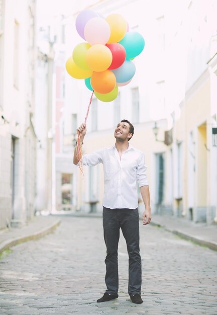 summer holidays, celebration and lifestyle concept - man with colorful balloons in the city