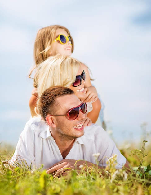 летние каникулы, концепция детей и людей - счастливая семья с голубым небом и зеленой травой