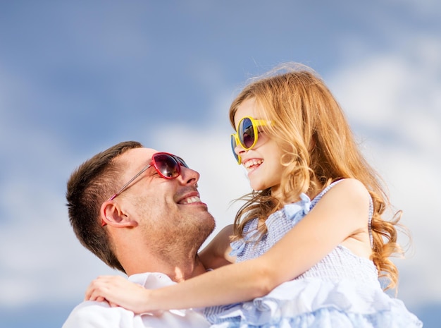 летние каникулы, дети и люди концепции - счастливый отец и ребенок в солнцезащитных очках над голубым небом