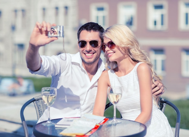 summer holidays and dating concept - couple taking photo in cafe in the city