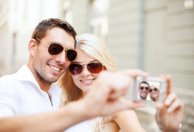 summer holidays and dating concept - couple taking photo in cafe in the city