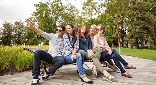 Vacanze estive, amicizia, tempo libero e concetto adolescenziale - gruppo di studenti o adolescenti che escono e agitano le mani nel campus o nel parco