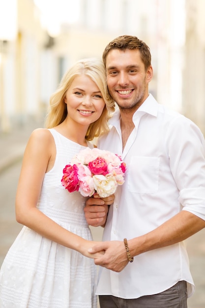 summer holidays, love, relationship and dating concept - couple with bouquet of flowers in the city