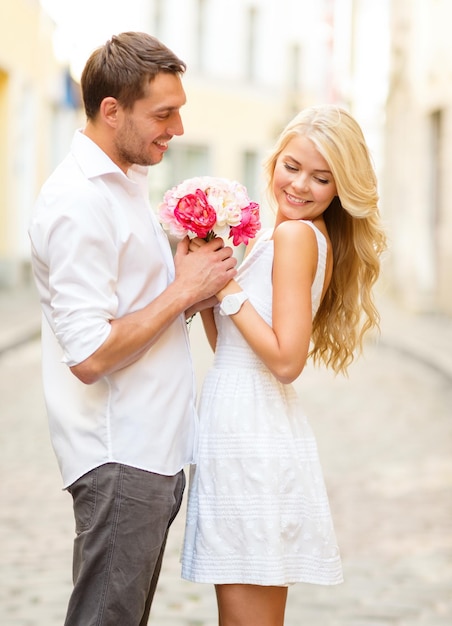 summer holidays, love, relationship and dating concept - couple with bouquet of flowers in the city