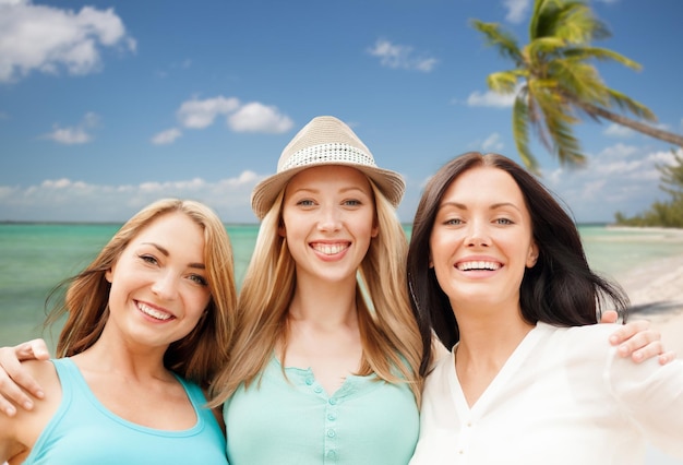 summer holidays, people, travel and vacation concept - group of smiling young women chilling over tropical beach background