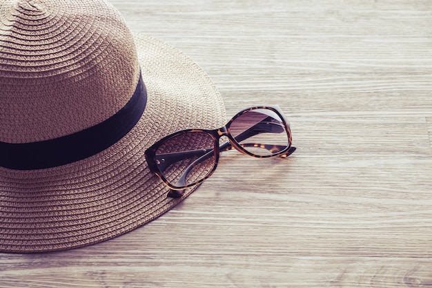 Summer holidays straw hat and sunglasses on wooden background