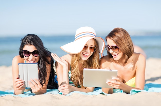 여름 방학, 기술 및 인터넷 개념 - 해변에서 일광욕을 하는 태블릿 PC와 비키니를 입은 소녀들
