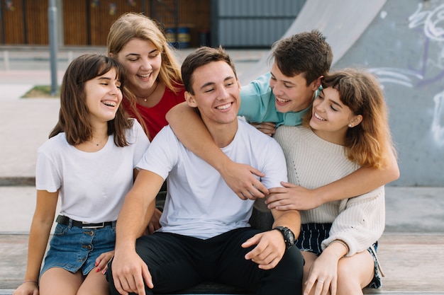 Summer holidays and teenage concept - group of smiling teenagers hanging out outside.