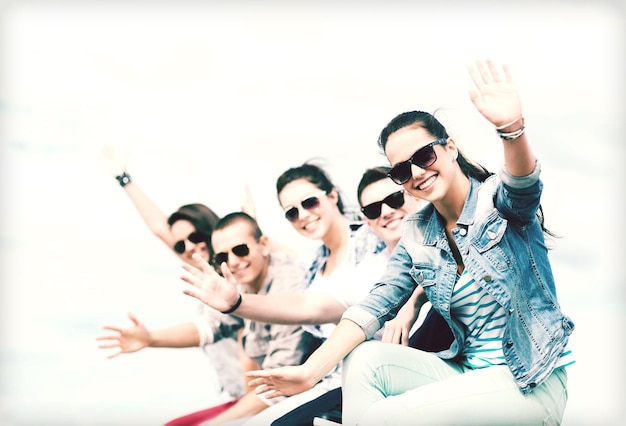 summer holidays and teenage concept - group of teenagers waving hands