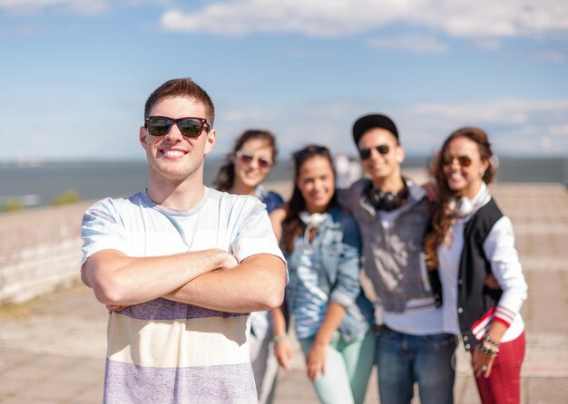 Vacanze estive e concetto di adolescente - ragazzo con gli occhiali da sole che esce con gli amici fuori