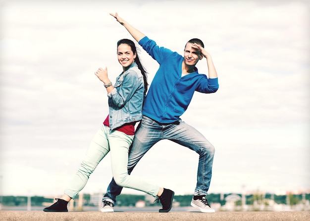 summer holidays, teenage and dancing concept - couple of teenagers dancing outside