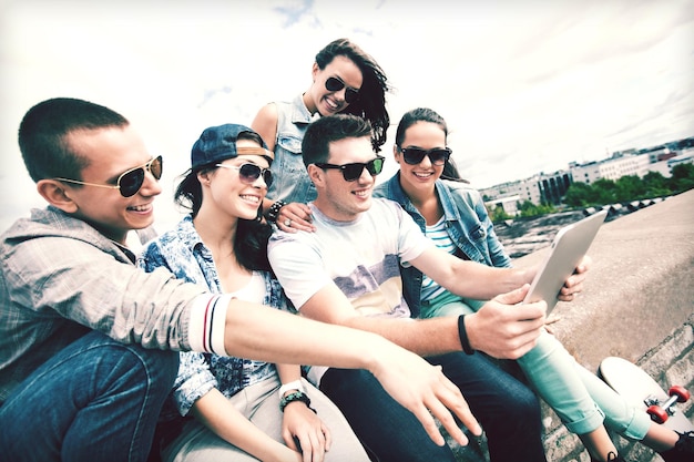 Photo summer holidays, teenage and technology concept - group of teenagers looking at tablet pc