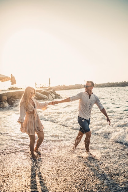 Summer holidays and travel Sexy woman and man in sea water at sunset Loving couple relax on the sunrise beach Love relationship of a couple enjoying a summer day together