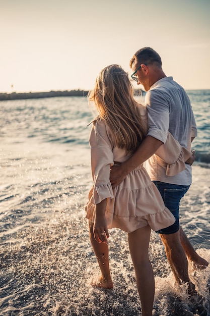 Foto vacanze estive e viaggi donna e uomo sexy in acqua di mare al tramonto coppia di innamorati rilassarsi sulla spiaggia dell'alba relazione d'amore di una coppia che si gode una giornata estiva insieme