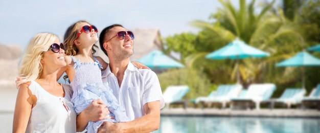 Foto concetto di vacanze estive, viaggi, turismo, vacanze e persone - famiglia felice sopra la piscina del resort dell'hotel e lo sfondo dei lettini