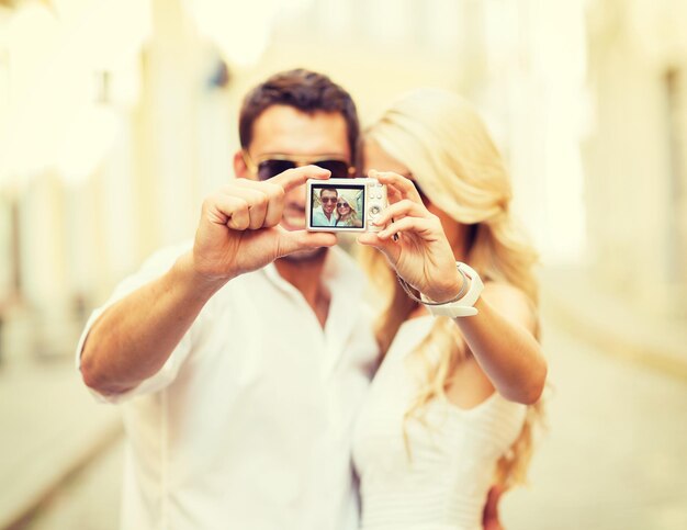 Photo summer holidays, travel, vacation, tourism and dating concept - travelling couple taking photo picture with camera