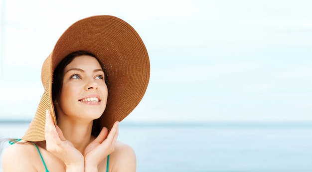 summer holidays and vacation concept - girl in hat standing on the beach