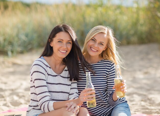 Vacanze estive e concetto di vacanza - ragazze con bevande sulla spiaggia