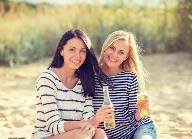 여름 휴가 및 휴가 개념 - 해변에서 음료수를 마시는 소녀들