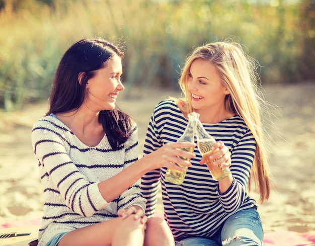 Photo summer holidays and vacation concept - girls with drinks on the beach