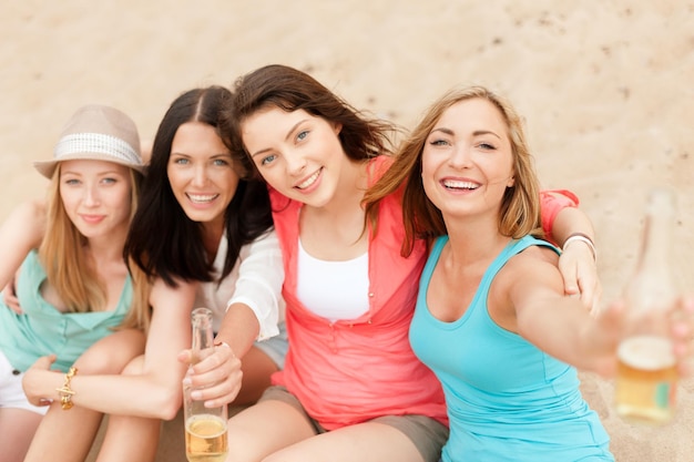 Vacanze estive e concetto di vacanza - ragazze sorridenti con drink sulla spiaggia