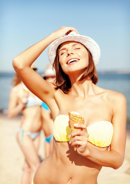 летние каникулы и каникулы - девушка в бикини ест мороженое на пляже