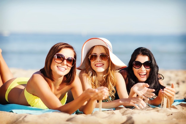 summer holidays and vacation - girls sunbathing on the beach