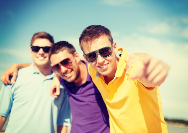 summer, holidays, vacation and happiness concept - group of friends having fun on the beach and pointing at you